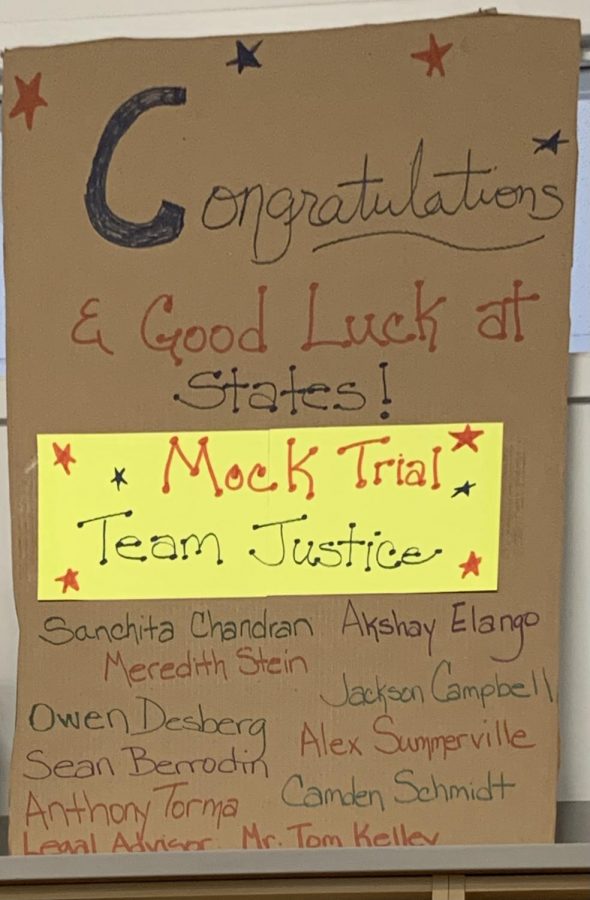 A sign hangs congratulating Team Justice on their qualification. 