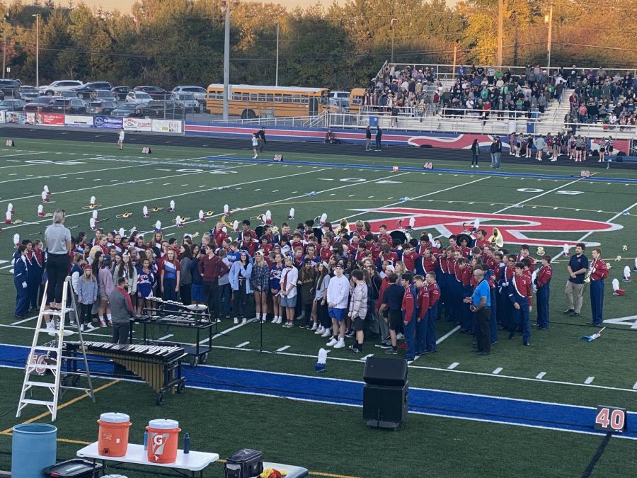 Choir and band students stand together, singing the National Anthem at the beginning of the football game. 