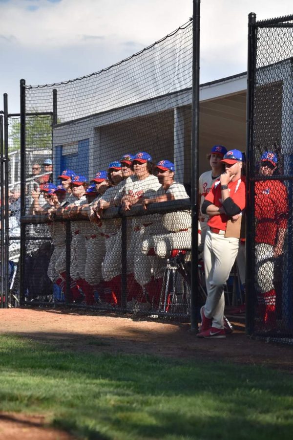Players stand against the fence, ready for the game to begin. 