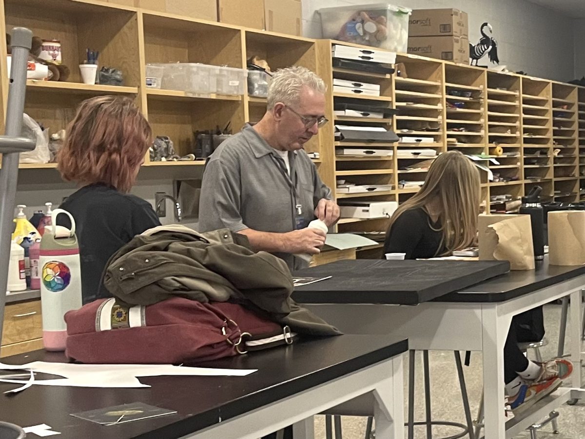 Bob Pierson assists a student with a project in his art class.