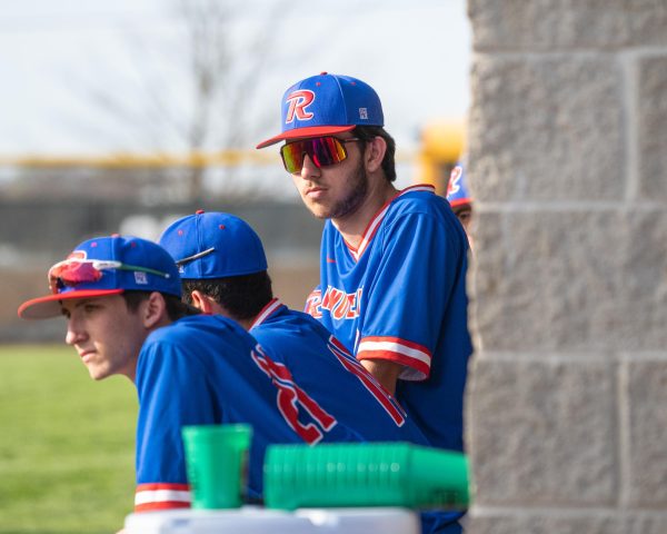 Phil Clark and the team watch live batters from dugout during the Revere vs. Highland game.