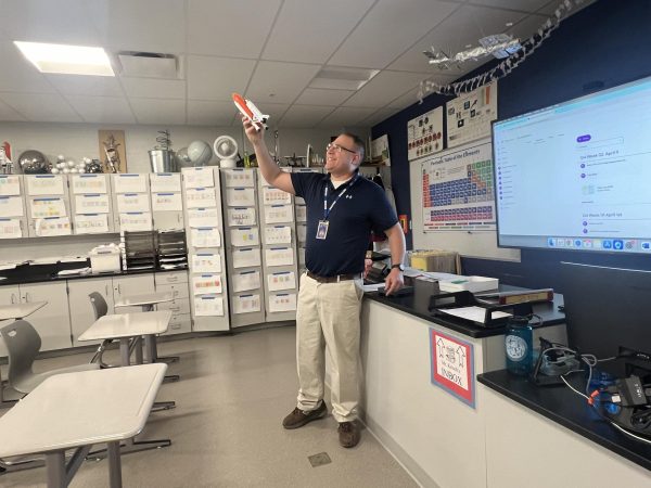 Robert Krisch teaches class of students using his model rocket. 