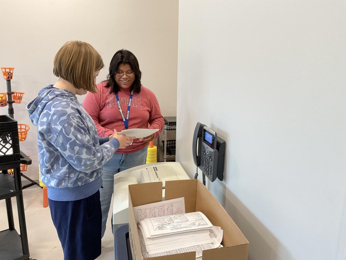 Ana Hair stands with one of her students as they shred paper.