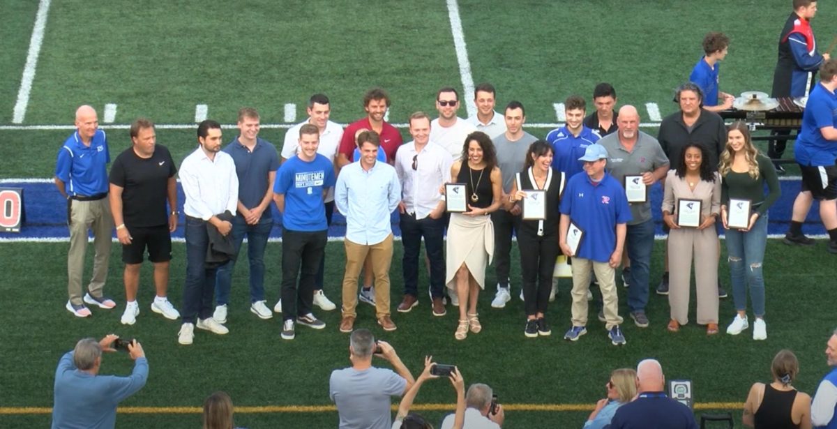 All recognized alumni stand on the RHS football field while holding their induction awards.