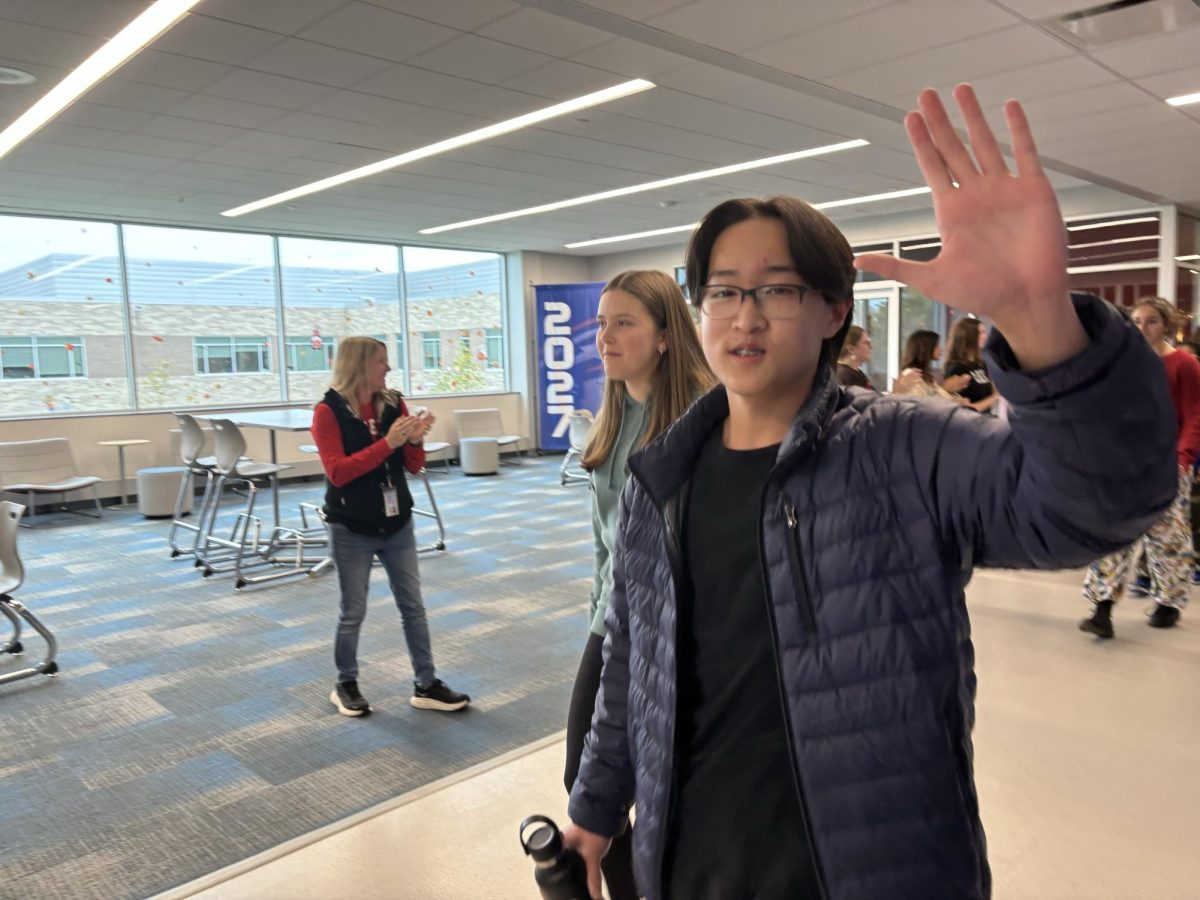 Du waves to the crowd during a school clap out for speech and debate.