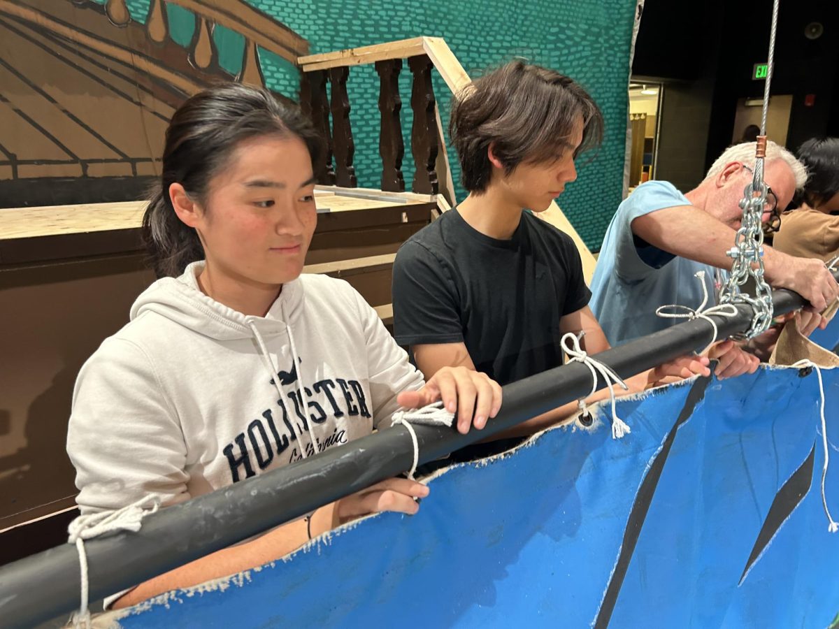 Weng helps set up a backdrop for the fall production.