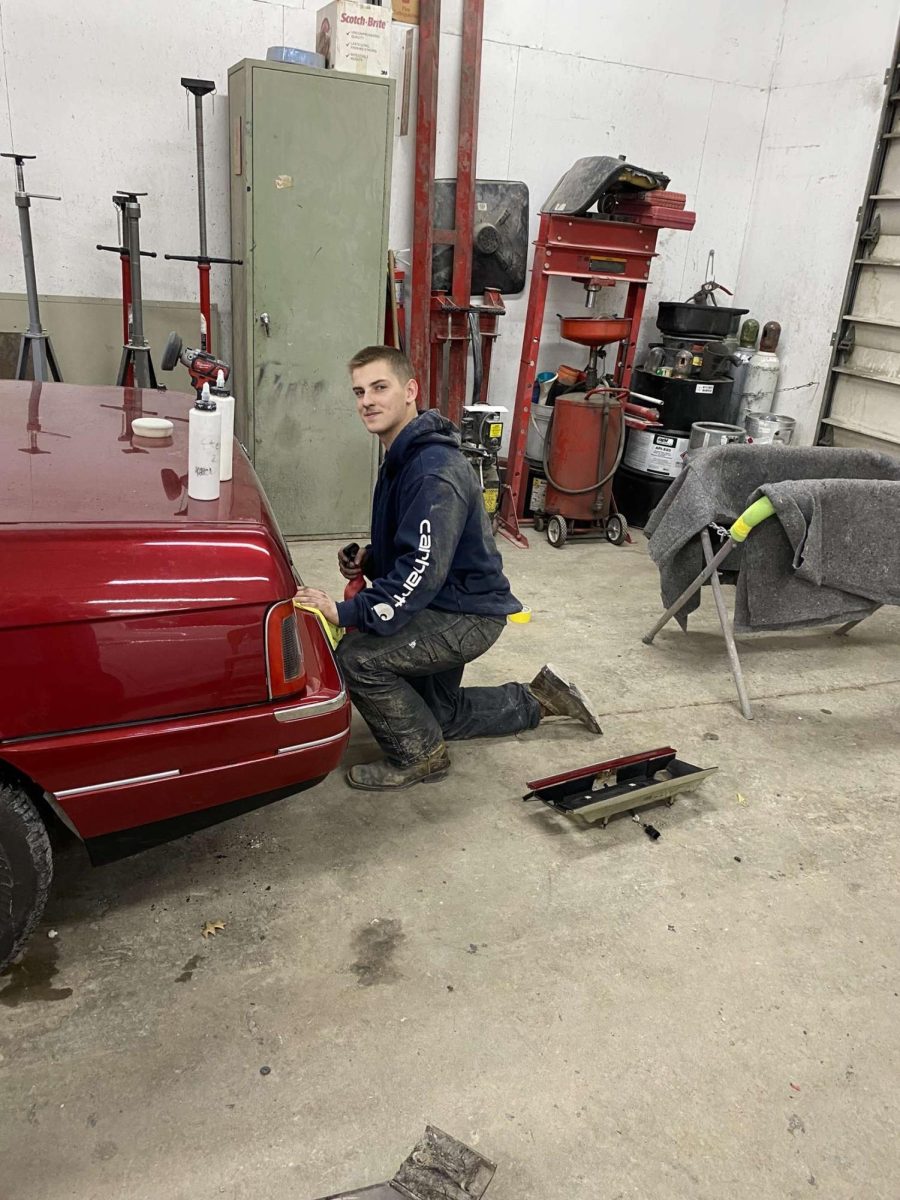 Yost touches up a cars bumper during his auto body job.