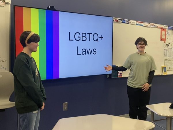 Spectrum Club members give a presentation on LGBTQ+ laws during a meeting.