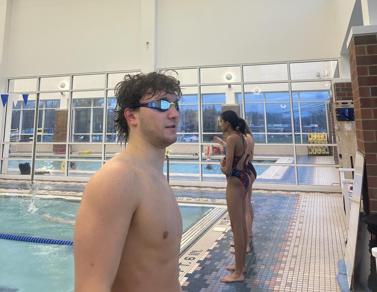 Junior Alex Koutris stands outside of the pool during a swim practice.