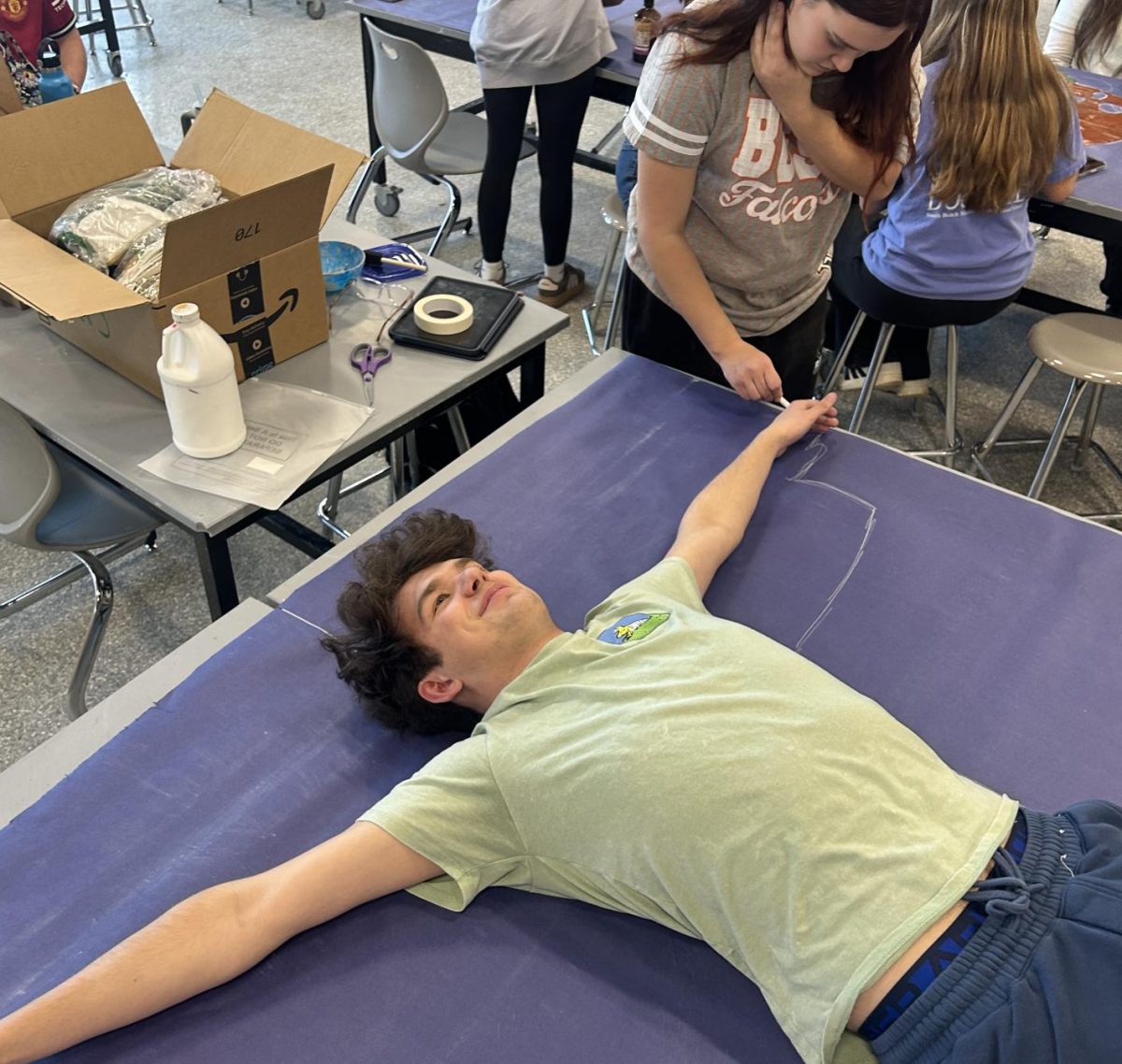Senior Tommy Long lays on a table during Art Club.
